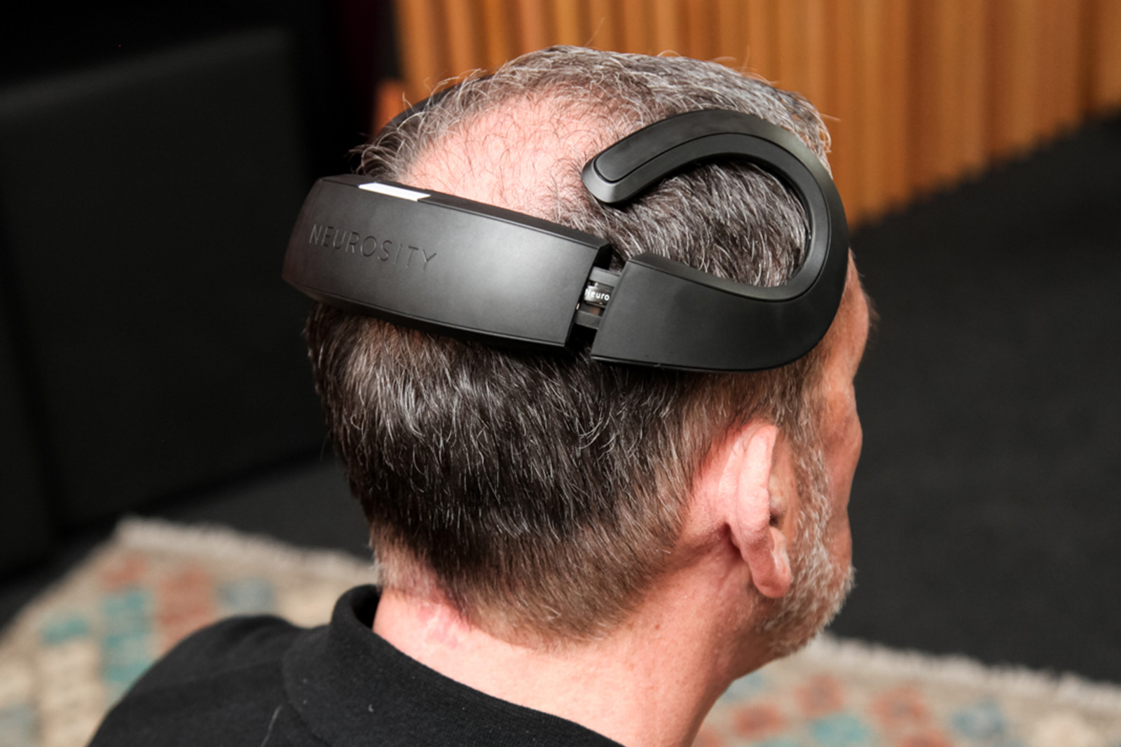 Eine Nahaufnahme von hinten, die einen Mann zeigt, der eine Neurosity Crown trägt – ein elegantes schwarzes Neurotechnologie-Headset zur Messung von Gehirnaktivitäten. Das Gerät umschließt den Hinterkopf und die Seiten mit speziellen EEG-Sensoren und wird häufig in Kombination mit VR-Therapie eingesetzt.